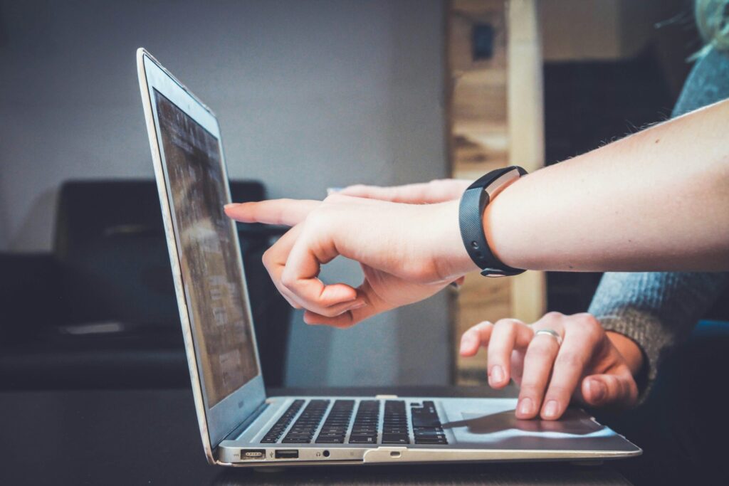 Someone pointing at a computer screen guiding someone through a technical process
